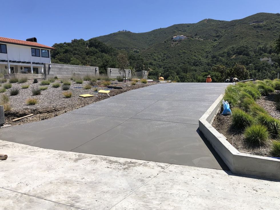 A large smooth concrete slab with a clean edge against a low retaining wall, dry hills behind it.